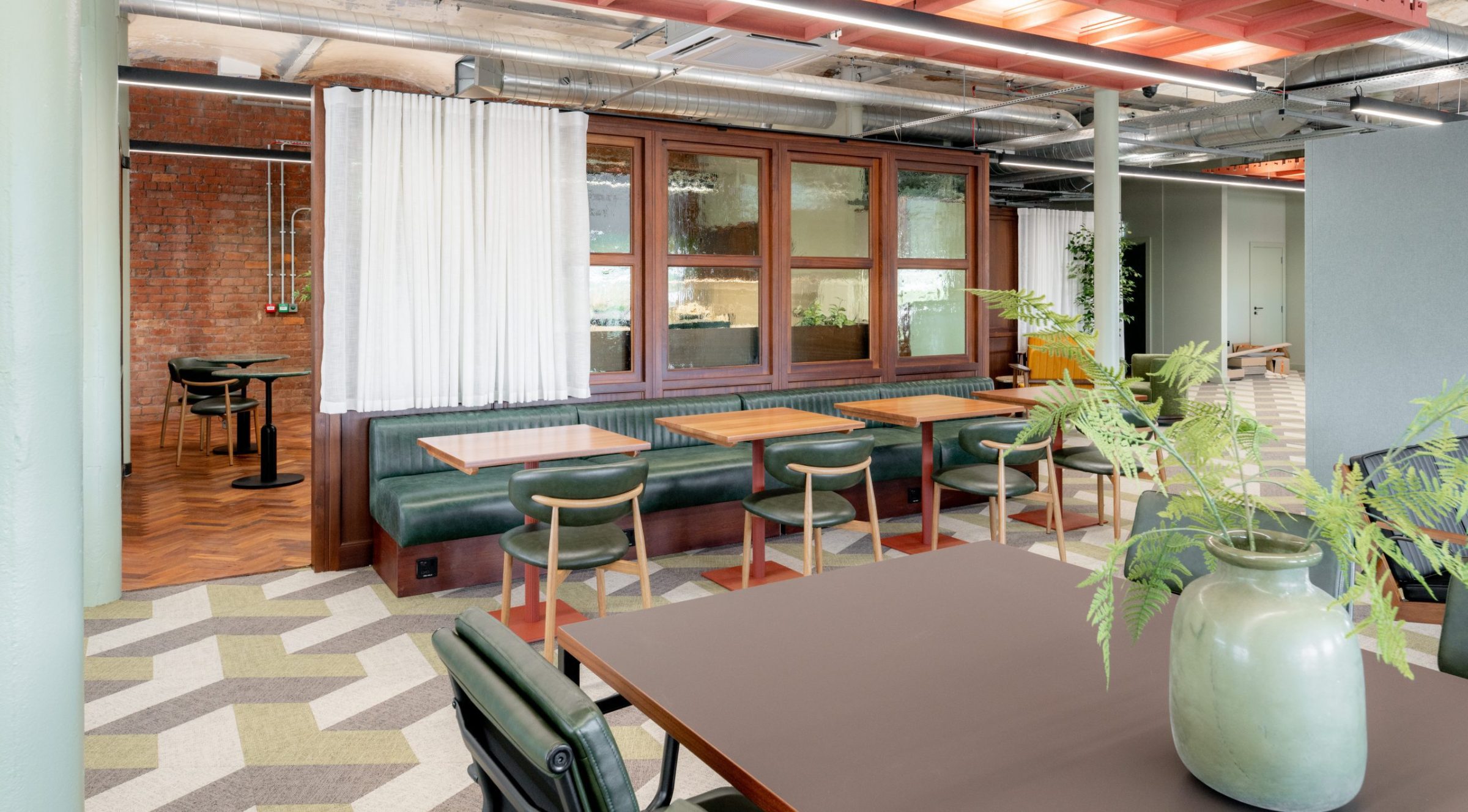Weave co-working space with banquettes, tables, and chairs arranged in zoned layout.
