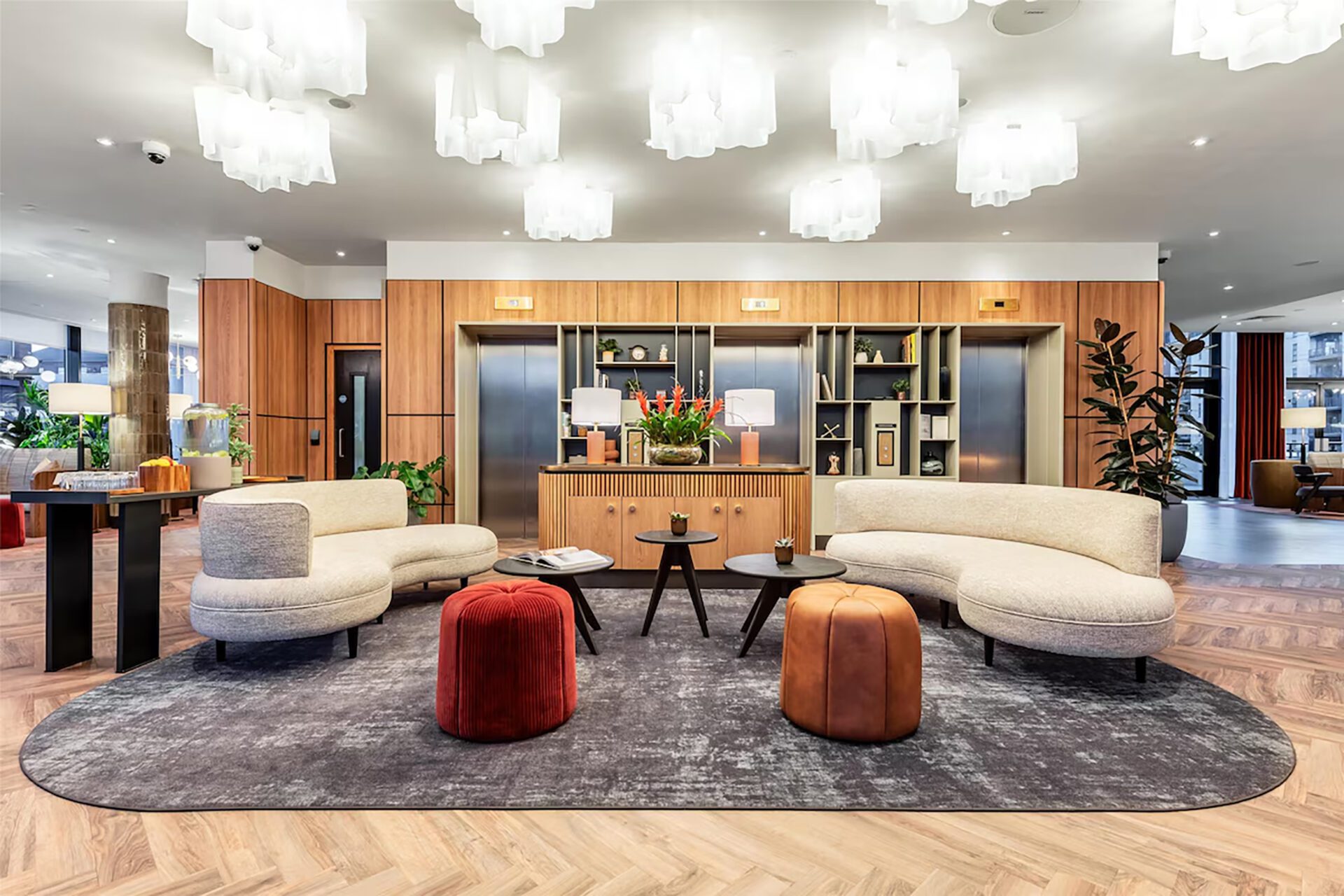 A multi-tasking hotel lobby furniture social cluster at the Park Inn Manchester, combining crescent sofas, poufs, and coffee tables curated by Bourne for bleisure travellers.